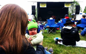 Baby wearing his headphones at a live music festival with his family.